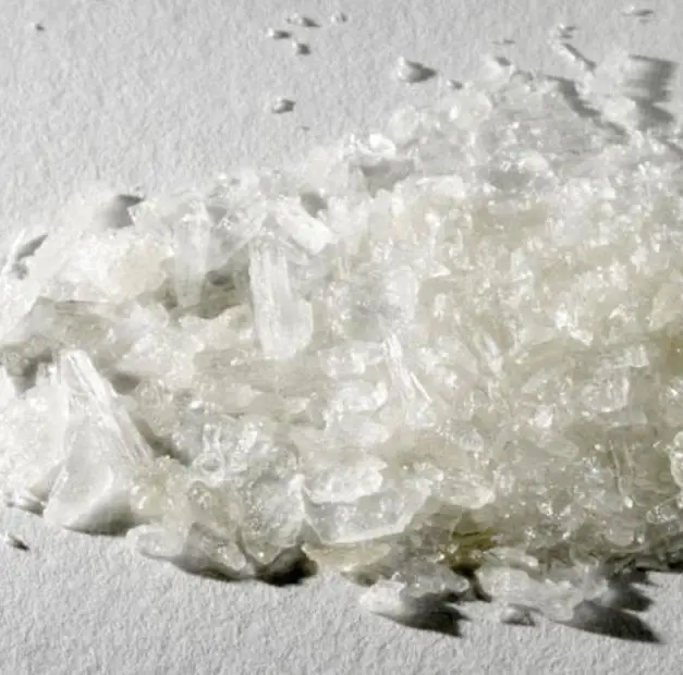 A pile of clear and white methamphetamine crystals of mixed size on a white surface